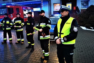 policjant drogówki w odblaskowej kamizelce, obok niego stoją strażacy-ochotnicy z Ornontowic