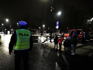 policjant drogówki stoi w odblaskowej kamizelce, obok przechodnie