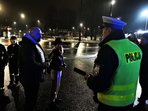 policjant drogówki rozmawia z pieszymi, scena ma miejsce w centrum Mikołowa, jest wieczór