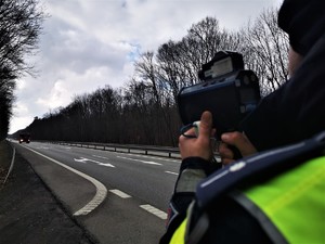 policjant drogówki w odblaskowej kamizelce stoi przy drodze krajowej numer 81 w Orzeszu i dokonuje pomiaru prędkości pojazdów