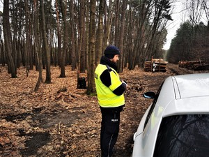 policjant drogówki w odblaskowej kamizelce stoi przy kontrolowanym samochodzie i rozmawia z kierującą