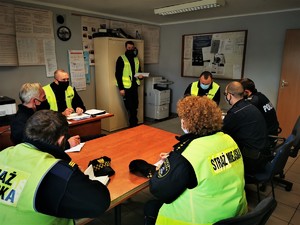 policjanci i strażnicy miejscy w sali odpraw podczas przygotowania do zabezpieczenia. Osoby te notują w swoich notatnikach