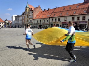 sportowcy biegnący z ukraińską flagą