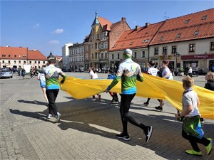 sportowcy biegną przez rynek z ukraińską flagą