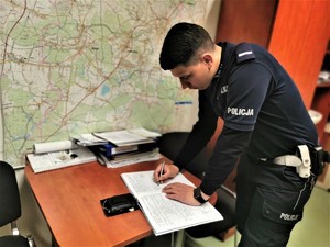 policjant drogówki w trakcie odprawy, w tle mapa powiatu mikołowskiego