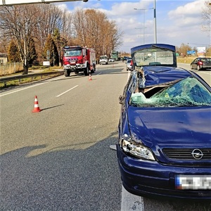 trasa drogi krajowej, uszkodzona karoseria granatowego opla, w tle inne pojazdy