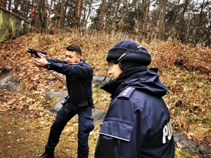 policjant prewencji trzyma broń i mierzy do celu, obok stoi pani instruktor