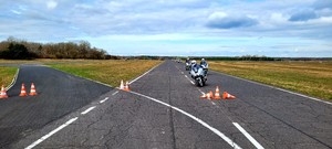 policjanci w trakcie szkolenia z jazdy motocyklem szosowym, zdjęcie wykonane na torze jazdy w ośrodku szkolenia. Panuje słoneczna aura