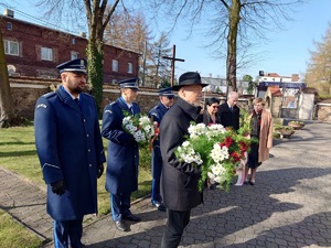 policjanci stoją przed miejscem pamięci poległych, obok przedstawiciele lokalnego samorządu