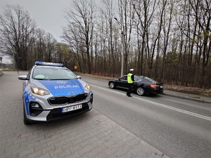 policyjny radiowóz, policjant wykonujący kontrolę kierującego osobówką