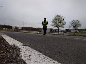 policjant drogówki stoi na ulicy, w tle droga krajowa