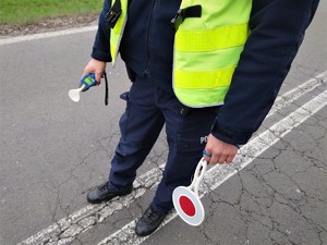 policjant drogówki trzyma w ręce tarczę oraz alkomat