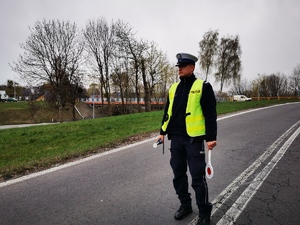 policjant w odblaskowej kamizelce stoi na drodze