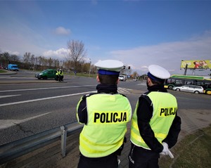 stojący przy trasie policjanci ruchu drogowego, w tle samochody