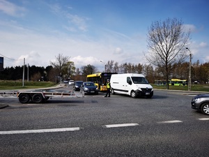 policjantka stoi na środku skrzyżowania i kieruje ruchem. Obok niej przejeżdżają samochody