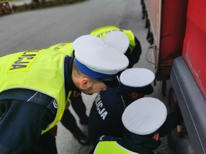 policjanci kucają przy ciężarowce, dokują kontroli jej stanu technicznego