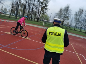 policjant przygląda się jeżdżącemu na rowerze chłopcu