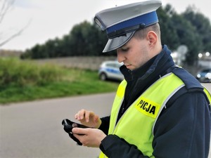 policjant drogówki dokonuje sprawdzenia w systemie na urządzeniu mobilnym