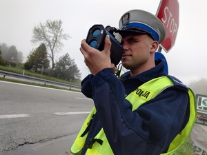 policjant drogówki mierzy prędkość kierowców