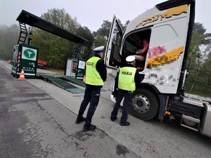 funkcjoanariusze stoją przy ciężarówce i rozmawiają z kierowcą