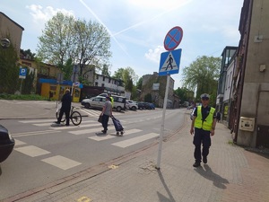 oznakowane przejście dla pieszych, ludzie przechodzą przez pasy, policjant idzie chodnikiem