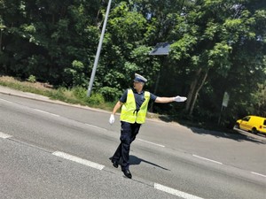policjant drogówki w odblaskowej kamizelce kieruje ruchem