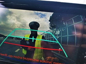 policjant drogówki w odblaskowej kamizelce w ekranie kamery cofania pojazdu