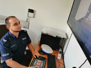 policjant drogówki wpatruje się w ekran miejskiego monitoringu. Zdjęcie robione w budynku Urzędu Miasta Mikołów