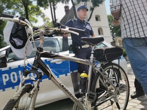 policjanci drogówki rozmawiają z rowerzystą, zdjęcie wykonane na terenie parkingu miejskiego