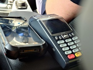 na podłokietniku samochodu leżą terminal płatniczy oraz urządzenie do kontroli w policyjnych systemach