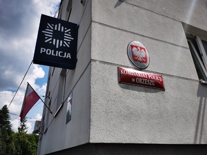 zdjęcie budynku komisariatu: flagi, logo Policji, tabliczka  z napisem: Komisariat Policji w Orzeszu