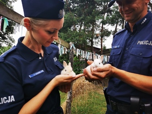 dwoje policjantów trzyma na rękach dwa małe króliczki