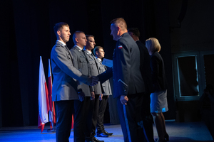 stojący na scenie awansowani policjanci, komendanci składają im gratulacje, scena w sali widowiskowej w Orzeszu