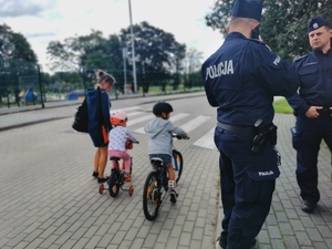 kobieta, obok niej dwoje dzieci, po prawej stronie policjanci