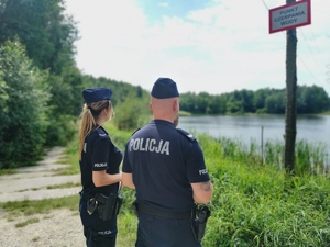 policjant i policjantka patrzą w kierunku zbiornika wodnego STARGANIEC
