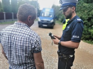 policjant drogówki, obok niego kierowca, w tle bus