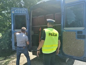 policjant drogówki w odblaskowej kamizelce, w tle bus i kierowca który otwiera tylne drzwi