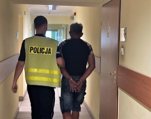 korytarz, policjant drogówki prowadzi zatrzymanego