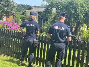 policjanci stoją przy płocie i prowadzą rozmowę z kobietą