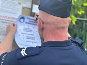 policjant przywiesza plakat na tablicy ogłoszeń