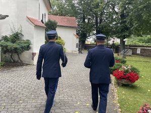 dwóch policjantów w mundurach galowych wchodzi na teren sanktuarium. Zdjęcie zrobione od tyłu