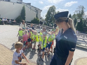 zdjęcie policjantki, za nią grupa małych dzieci, w powietrzu latają bańki mydlane