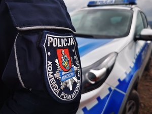 fragment policyjnego radiowozu oraz naszywka na mundurze: Komenda Powiatowa Policji w Mikołowie