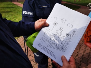 policjant trzyma w ręce plik kolorowanek dla dzieci