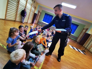 policjant rozdaje dzieciom opaski