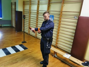 policjant prezentuje prawidłowy sposób założenia odblaskowej opaski