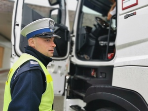 zdjęcie kolorowe: policjant drogówki stoi obok ciężarówki