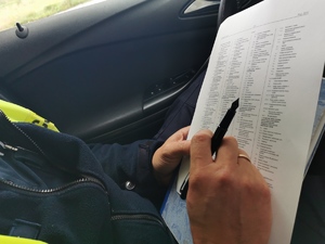 policjant drogówki wypełnia dokumenty siedząc w radiowozie
