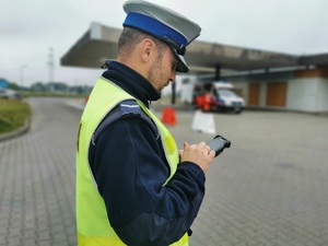 policjant drogówki dokonuje legitymowania w urządzeniu mobilnym