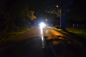 zdjęcie kolorowe: droga, jest ciemno, widać stojący na jezdni samochód marki volkswagen